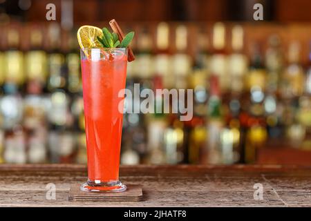 Cocktail fruit Sling long verre sur le fond flou du comptoir de bar, image pour le menu. Boisson alcoolisée congelée Banque D'Images