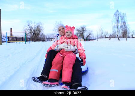 Maman et fille passent un tubing en hiver. La famille passe du temps dehors en hiver. Jeux de luge Banque D'Images