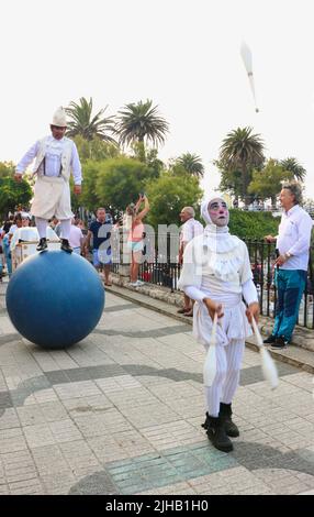 Spectacle public des artistes de cirque de Bambolea dans la rue près de Piquio Santander Cantabria Espagne avec un homme qui se balance sur une grande boule bleue et un jongleur Banque D'Images