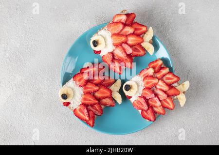 Sandwiches doux pour les enfants en forme de poissons avec fraises, banane, fromage à la crème et flocons de noix de coco, idée culinaire pour les fêtes d'enfants Banque D'Images