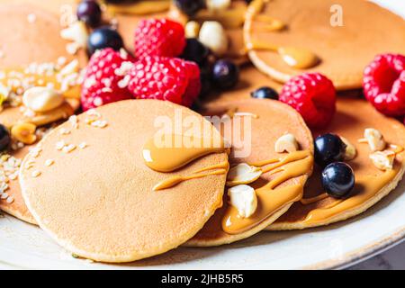 Crêpes maison d'été avec framboises, raisins de Corinthe et beurre d'arachide, gros plan. Crêpes aux flocons d'avoine végétaliens. Banque D'Images