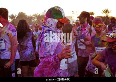 Jeune femme arabe souriante couverte de poudre colorée, danse à la Color Walk à Dubaï, Émirats arabes Unis. Chapeau aux couleurs drapeau des Émirats arabes Unis au-dessus de son hijab. Banque D'Images