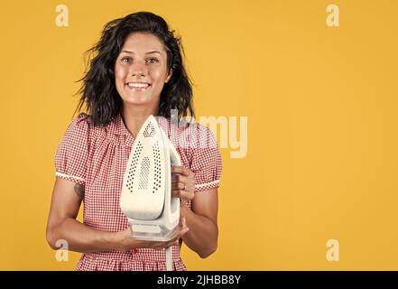 concept de la tenue au foyer. fer vapeur. préparation du repassage par une petite fille. femme vintage tenant un fer moderne. La vie quotidienne et les travaux ménagers. Femme rétro avec fer à repasser Banque D'Images