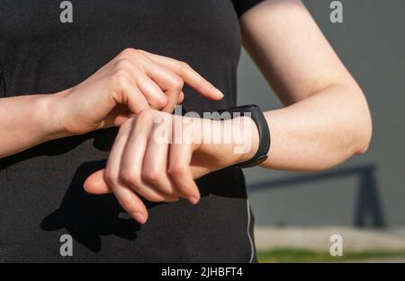 Femme utilisant un tracker d'activité pour le contrôle du nombre d'étapes ou de la fréquence cardiaque. Les mains des femmes en gros plan. Concept de mode de vie sain. Appareil d'entraînement. Photo de haute qualité Banque D'Images