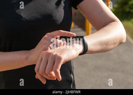 Femme utilisant un tracker d'activité pour les marches à pied, la distance de course ou la surveillance de la fréquence cardiaque. Les mains des femmes en gros plan. Amélioration du bien-être physique. Photo de haute qualité Banque D'Images