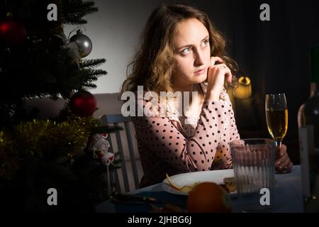 Jeune fille s'ennuie et boire du champagne à l'approche du Nouvel An Banque D'Images