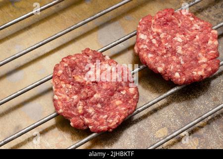 Hamburgers de bœuf cru sur le gril. Vue de dessus. Arrière-plan en métal rouillé. Banque D'Images