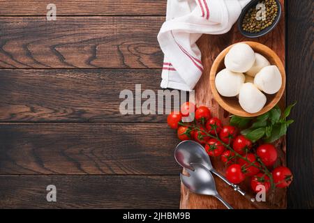 Salade Caprese, ingrédients pour la cuisine. Découpe de bois avec préparation traditionnelle de caprese ingridients: Mozzarella, tomates, basilic, olive oi Banque D'Images