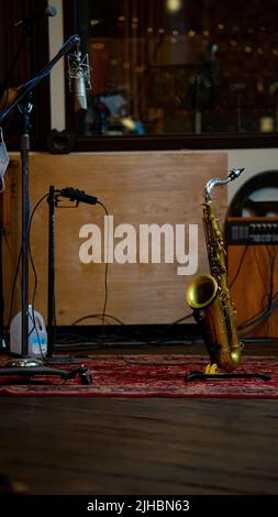 Un cliché vertical d'un saxophone sur un stand dans une salle avec un appareil d'enregistrement Banque D'Images