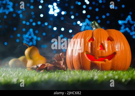 Bannière Halloween, carte postale, affiche, invitation. Composition d'Halloween. Grande citrouille orange avec un sourire sinistre, fruits d'automne, cônes sur une pelouse verte Banque D'Images