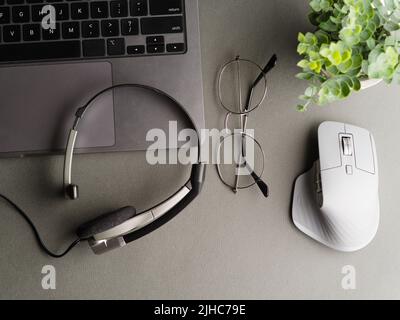 Le lieu de travail d'un étudiant, homme d'affaires, indépendant, journaliste, blogueur. Sur le bureau, un ordinateur portable, un casque, une souris, des lunettes et une fleur en pot o Banque D'Images