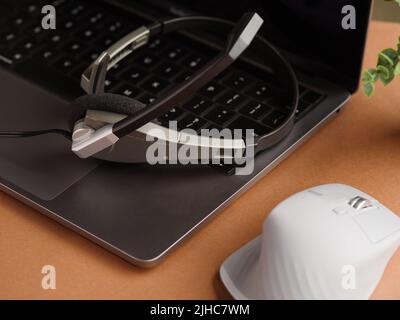 Gros plan. Casque sur ordinateur portable, souris d'ordinateur sur fond beige. Bureau, bureau à domicile, lieu de travail d'un programmeur, musicien, blogueur, journaliste, Banque D'Images