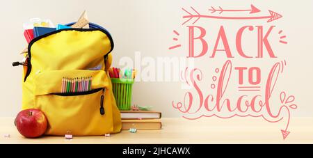 Sac à dos avec articles de papeterie et pomme sur table sur fond clair. Retour à l'école Banque D'Images