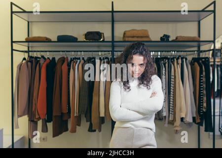 Jeune femme contrariée et triste se tenant dans un magasin de vêtements dans un centre commercial, les mains pliées, insatisfaite. Il attend un assistant, un consultant. Je n'ai rien acheté, je n'ai rien choisi Banque D'Images