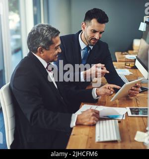 Le monde en ligne leur permet de catapulter leur avance d'affaires : deux hommes d'affaires travaillant sur une tablette numérique dans un bureau. Banque D'Images