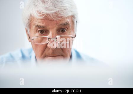 S'est concentré sur son entreprise. Un homme d'affaires très expérimenté travaillant sur son ordinateur à la maison. Banque D'Images