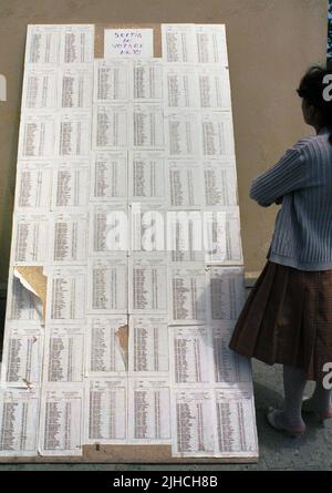 Comté d'Ilfov, Roumanie, 20 mai 1990. Les premières élections démocratiques après la chute du communisme. Femme locale regardant les listes à l'extérieur des sondages. La plupart des gens ont voté pour la première fois dans leur vie. Banque D'Images