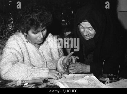 Comté d'Ilfov, Roumanie, 20 mai 1990. Les premières élections démocratiques après la chute du communisme. Les employés du sondage aident une femme âgée à signer son nom. La plupart des gens votaient pour la première fois dans leur vie et certains ne pouvaient pas écrire. Banque D'Images