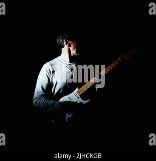 Homme mature tenant une guitare acoustique sur fond noir. Portrait d'un homme mature tenant une guitare acoustique sur fond noir. Banque D'Images