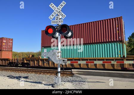 Hoffman Estates, Illinois, États-Unis. Signaux clignotants à un passage à niveau de chemin de fer protégé par l'appareil lorsqu'un train de marchandises intermodal passe. Banque D'Images