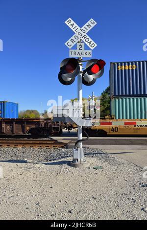 Hoffman Estates, Illinois, États-Unis. Signaux clignotants à un passage à niveau de chemin de fer protégé par l'appareil lorsqu'un train de marchandises intermodal passe. Banque D'Images