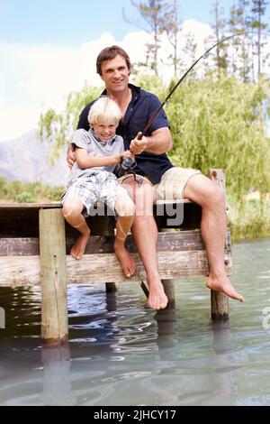 Tu lui fais maintenant mon garçon. Un père et un fils excités qui se défont dans un poisson et sourient. Banque D'Images