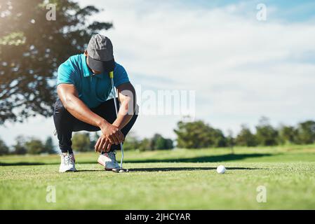 C'était si près. Un jeune golfeur masculin concentré regardant le sol tout en étant assis sur l'herbe dehors pendant la journée. Banque D'Images