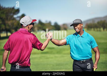 Nous sommes tous les deux sur notre jeu aujourd'hui. Deux jeunes joueurs de golf joyeux s'engageant dans une poignée de main après un grand tir sur le terrain de golf. Banque D'Images