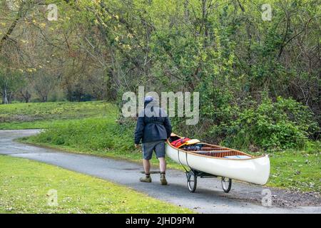 Issaquah, Washington, États-Unis. Homme tirant son canot sur un tas pour le transporter au lac Sammamish. (M.) Banque D'Images