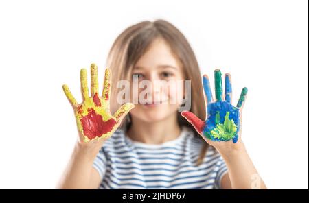 Une petite écolière montre des mains peintes avec des aquarelles - isolées sur du blanc. Banque D'Images