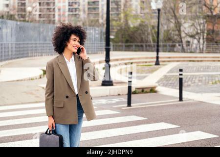 une femme d'affaires se promène dans la ville et parle par téléphone Banque D'Images
