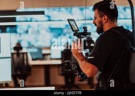 Vidéaste professionnel avec vidéo slr de gimball enregistrant la vidéo des opérateurs de centre de données de sécurité tout en travaillant dans une salle de surveillance de CCTV regardant Banque D'Images