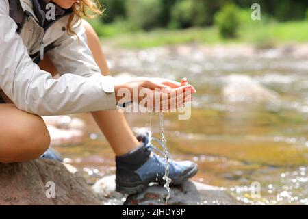 Gros plan d'un trekker avec des mains en forme de cupped qui attrapent l'eau de la rivière dans la montagne Banque D'Images