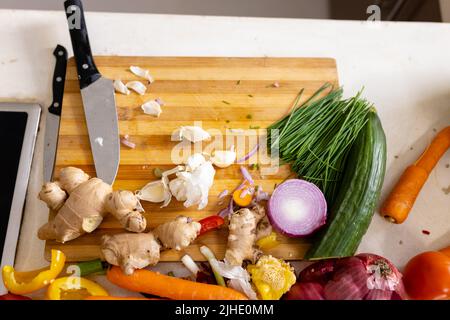 Vue en grand angle des légumes avec gingembre, ail, restes, planche à découper et couteau sur l'île Banque D'Images