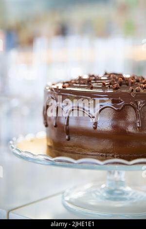 Délicieux gâteau au chocolat avec glaçage goutte à goutte de ganache et décoration simple avec des copeaux de chocolat noir sur un support en verre Banque D'Images