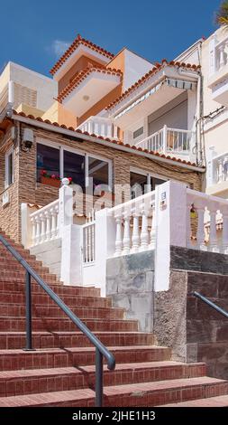 Architecture des maisons locales avec de grandes fenêtres et des murs colorés construits sur les collines et les terrasses entourant le petit village côtier, la Caleta Banque D'Images