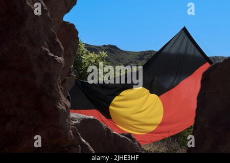 Le drapeau aborigène de l'Australie se déroula entre les Ancient Rocks Banque D'Images