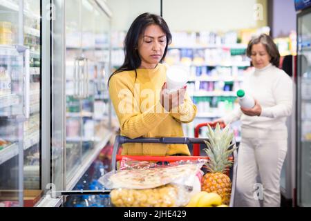 Femme hispanique magasiner pour des produits laitiers dans un supermarché Banque D'Images