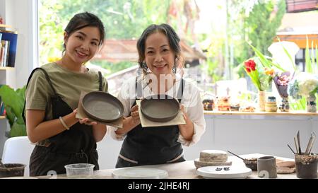 Une jeune femme asiatique heureuse et une femme mature aiment faire de la céramique dans un atelier de poterie Banque D'Images