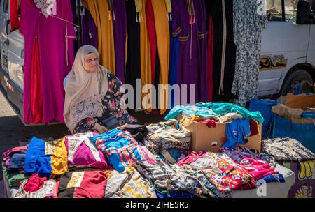 Une femme âgée vend ses vêtements au Sunday Souk, un marché de Souk à Sousse, en Tunisie. Banque D'Images