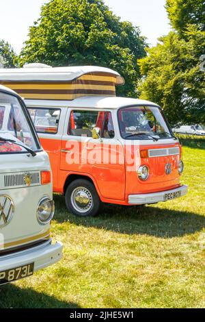 deux camping-cars volkswagen, l'un orange avec toit pop-top, l'autre crème Banque D'Images