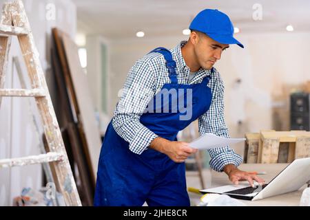 Un technicien vérifie les documents et utilise un ordinateur portable pendant les travaux de réparation Banque D'Images
