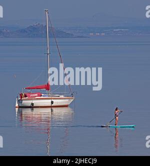 Portobello, Édimbourg, Écosse, Royaume-Uni. 18th juillet 2022. La température augmente avec 23 degrés centigrade seulement after10am, a augmenté jusqu'à 29 degrés centigrade en 1pm. Photo : paddleboarder cool appréciant le calme Firth of Forth avec Inchkeith Island en arrière-plan. Banque D'Images