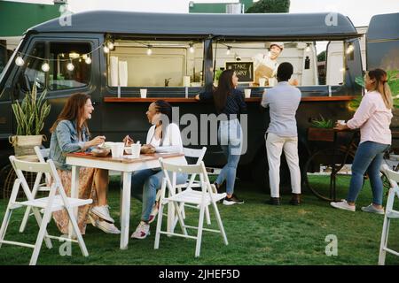 Les clients des camions alimentaires discutent entre eux et avec le fournisseur Banque D'Images