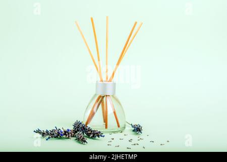 Bouteille en verre de diffuseur en roseau et fleur de lavande sur fond vert clair. Gros plan. Banque D'Images