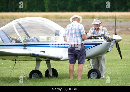 Les pilotes effectuent un contrôle avant vol sur le moteur Rotax dans un avion léger EV-97 TeamEurostar à un aérodrome au Royaume-Uni Banque D'Images