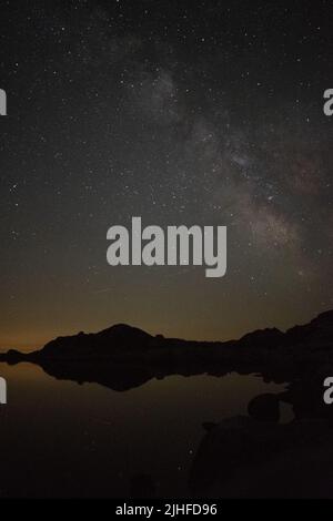 Milky Way qui s'élève au-dessus d'un lac glaciaire dans le parc national de Retezat. Banque D'Images