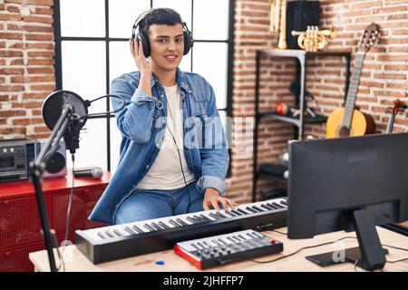 Jeune homme non binaire musicien jouant un clavier de piano dans un studio de musique Banque D'Images