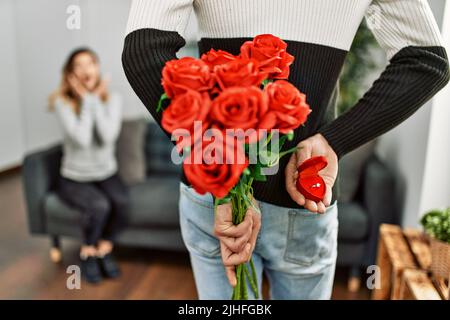 Homme femme suprising avec bouquet de roses et anneau d'engagement à la maison. Banque D'Images