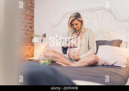 jeune femme enceinte à l'écoute du cœur de son bébé, plein coup. Photo de haute qualité Banque D'Images